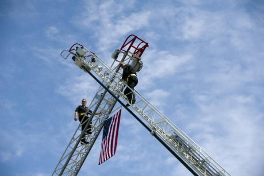 For Loudon Bridge Day, the city of Loudon Fire Department, left, and the Lenoir City Fire Department used their ladder trucks to hang a flag over the Veterans Memorial-John Duncan Bridge on Sunday, September 11, 2011. 
  
 (Saul Young/News Sentinel)
