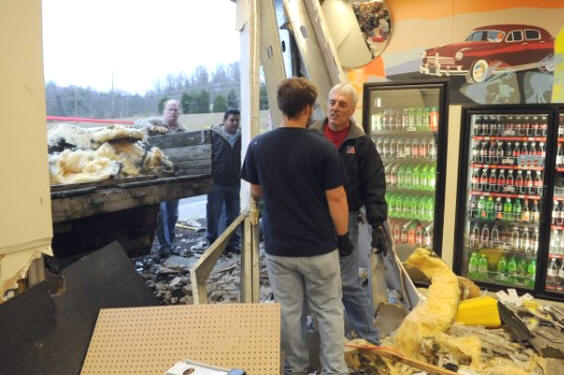 Employees Stephen Brown, center, and Dune Drinnon, right, talk to one another as they clean up the mess created when a car slammed into the side of the TravelCenters of America gas station on Watt Road on Friday.  An unidentified female driver accidentally hit the gas pedal as she was parking her car and drove into the side of the store at approximately 1:45 p.m., according to the store's general manager, Randy Smith.  (ADAM BRIMER/NEWS SENTINEL)

